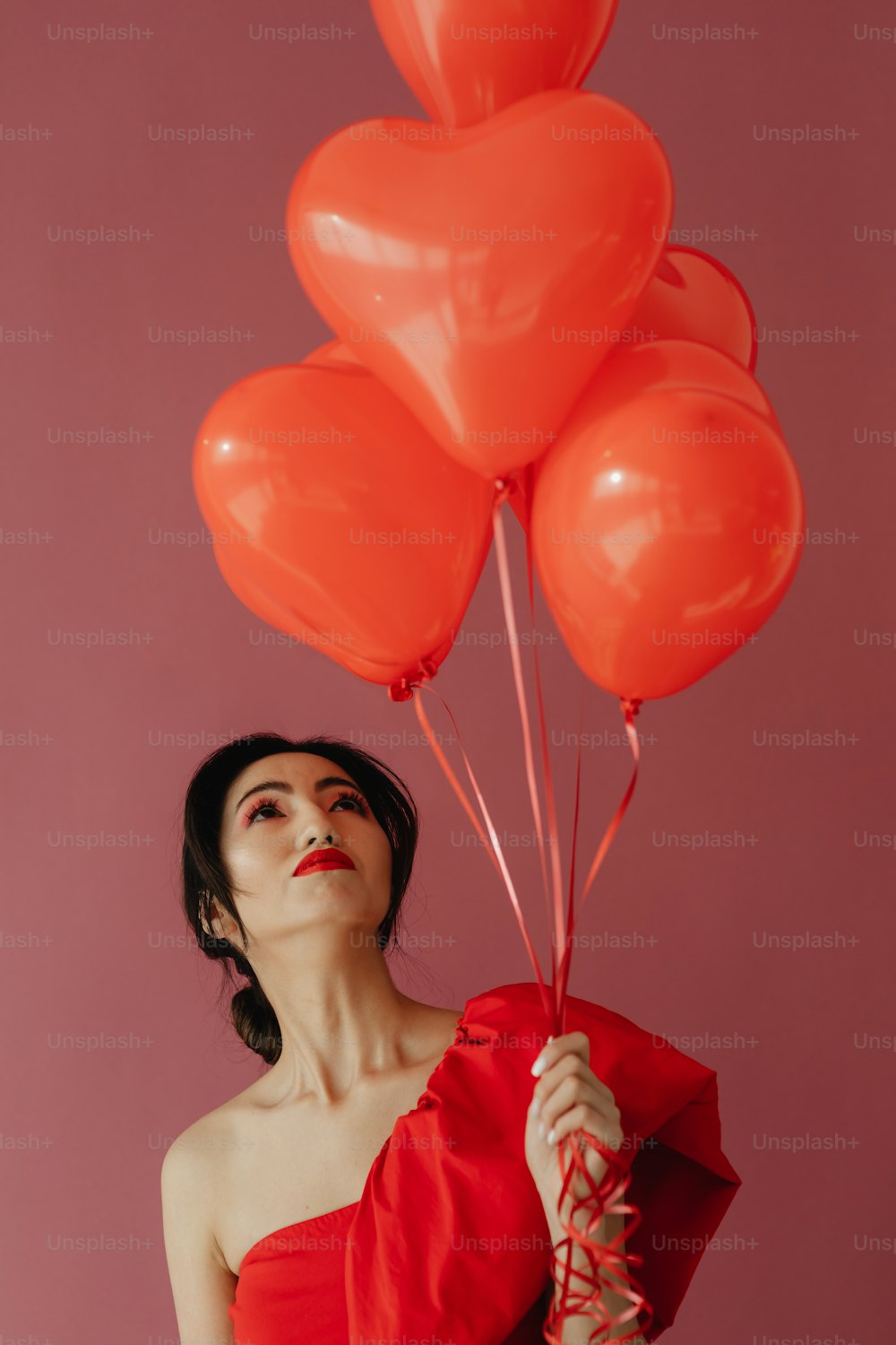 赤い風船の束を持つ女性