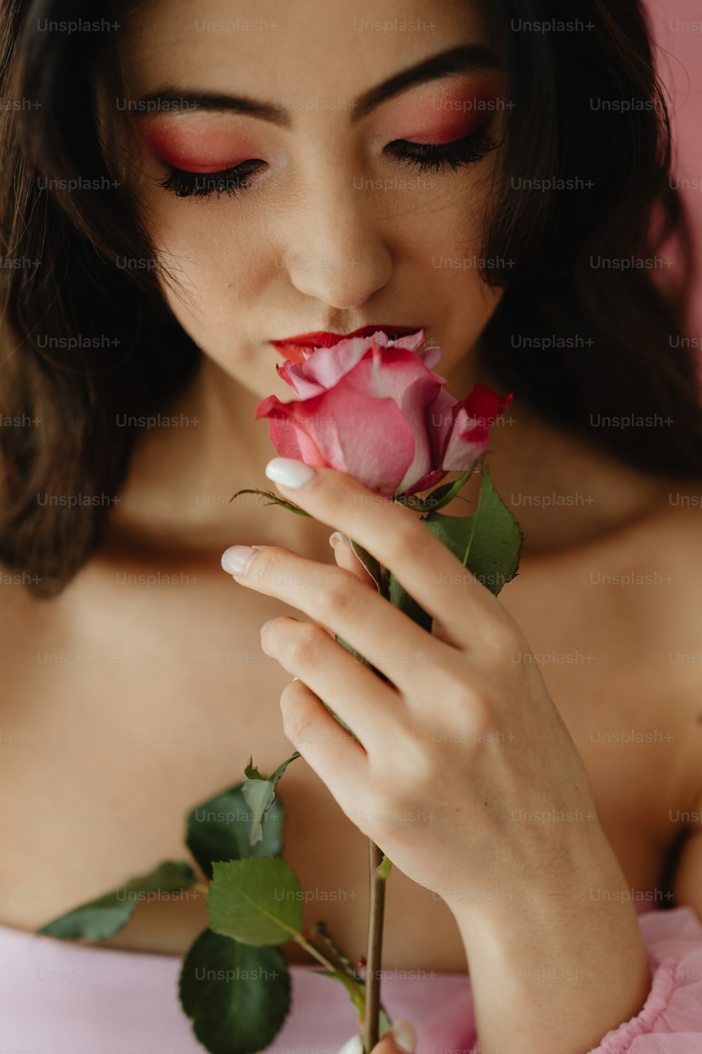 Una mujer con un vestido rosa sosteniendo una rosa
