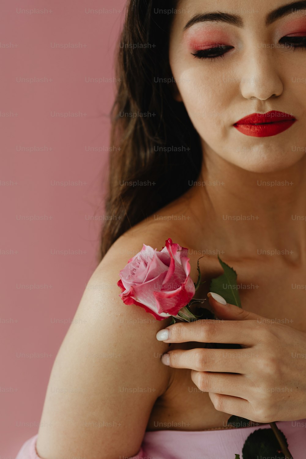 uma mulher em um vestido rosa segurando uma rosa