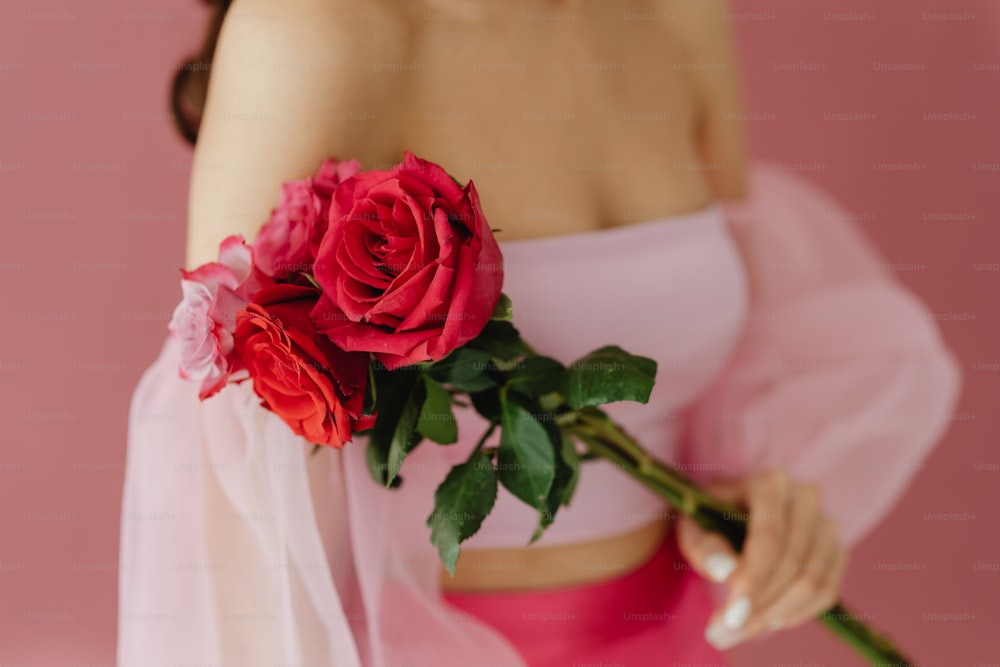 uma mulher em um vestido rosa segurando uma rosa vermelha