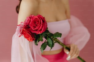 a woman in a pink dress holding a red rose
