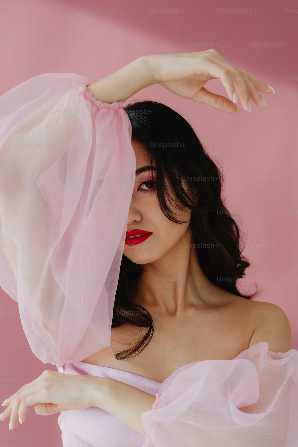 Una mujer con un vestido rosa con un velo sobre la cabeza