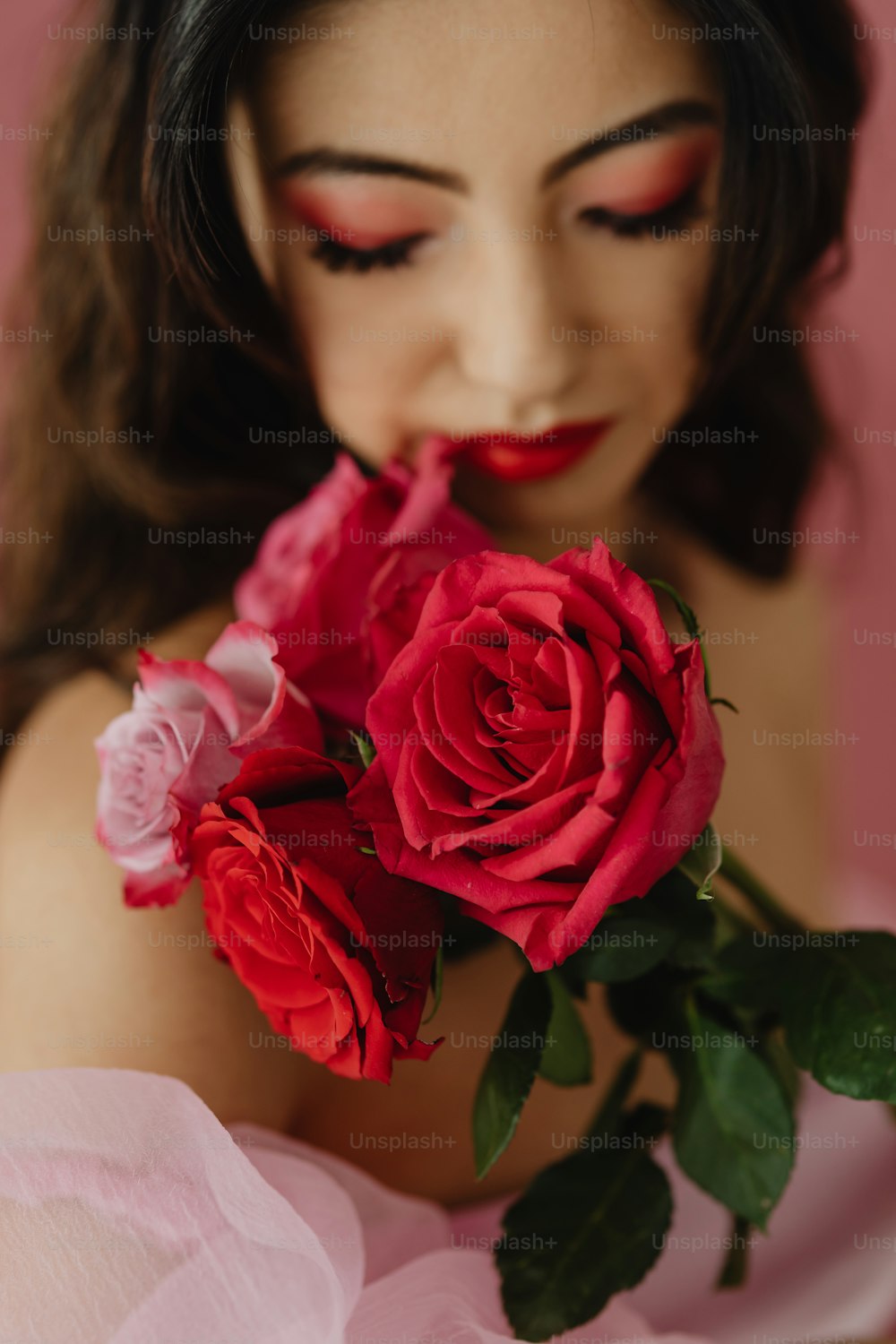a woman in a pink dress holding a bouquet of roses