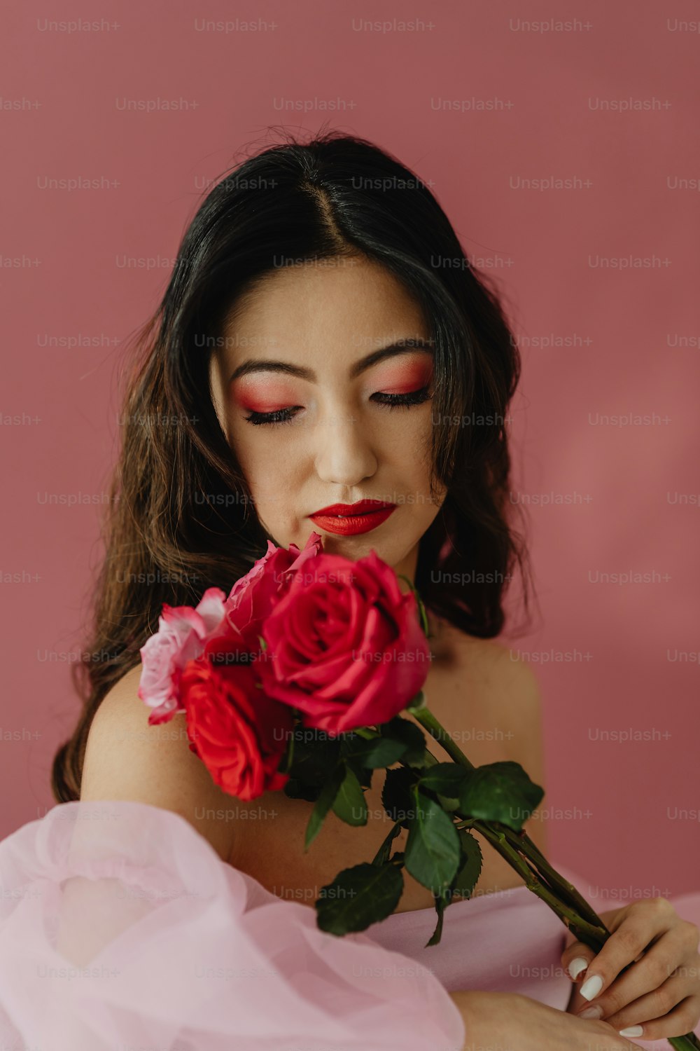 uma mulher em um vestido rosa segurando uma rosa