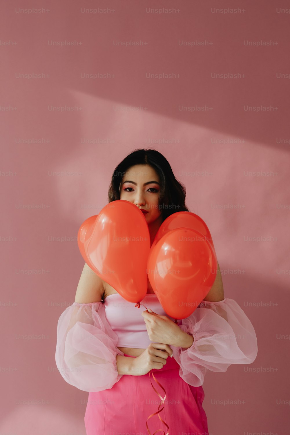 a woman in a pink dress holding balloons