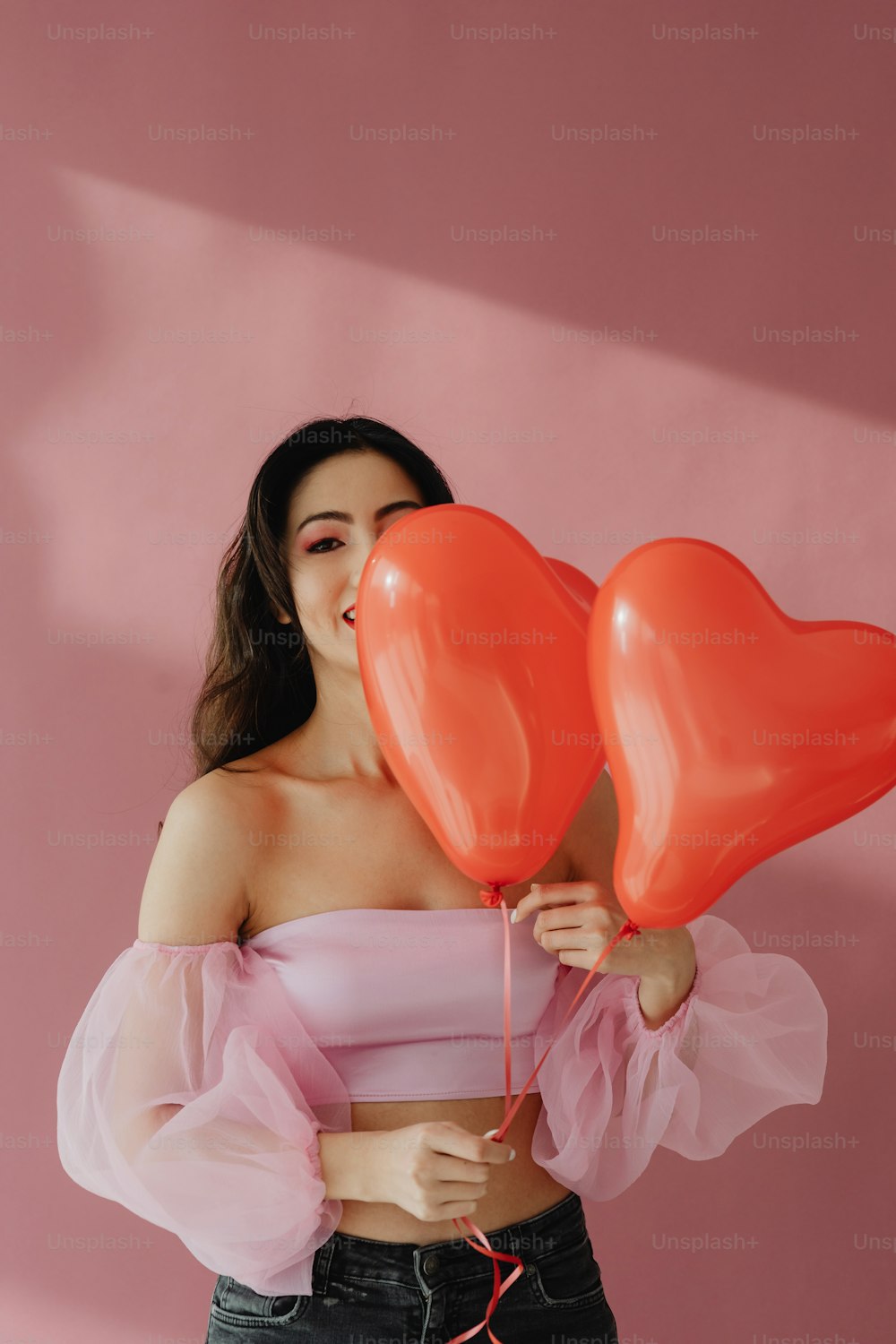a woman holding two heart shaped balloons in her hands