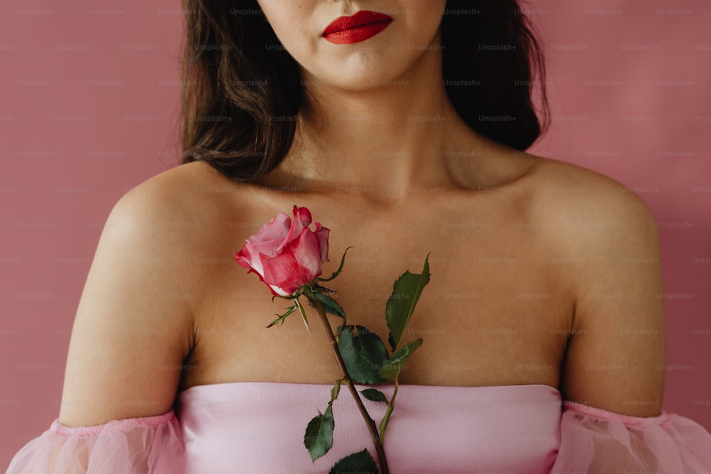 a woman in a pink dress holding a rose