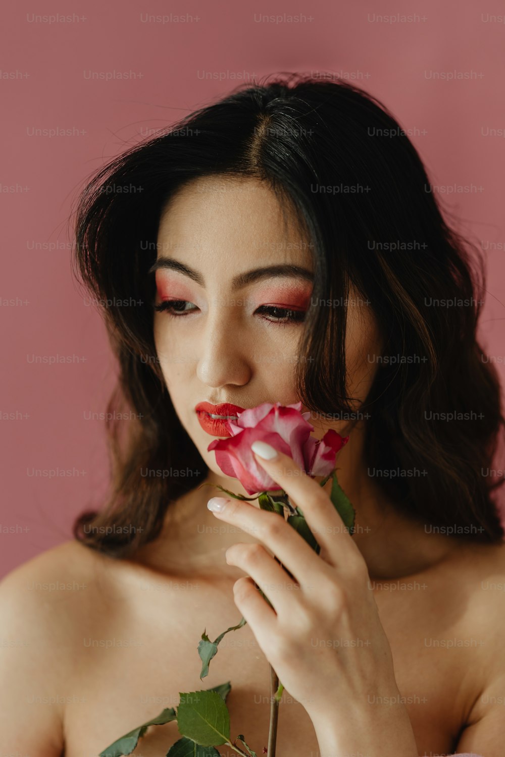 uma mulher segurando uma rosa até o rosto