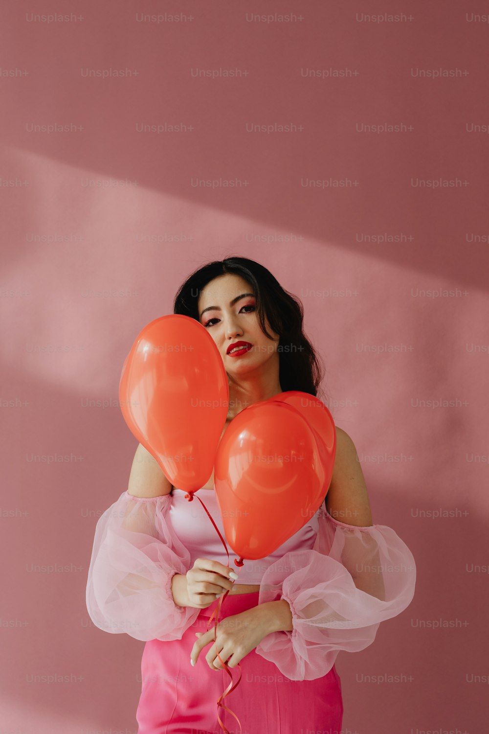 Una mujer con un vestido rosa sosteniendo globos