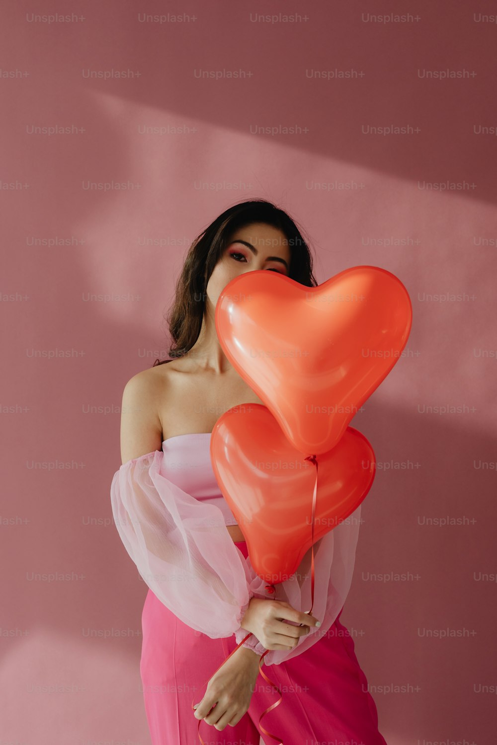 Una mujer sosteniendo un montón de globos de corazón rojo