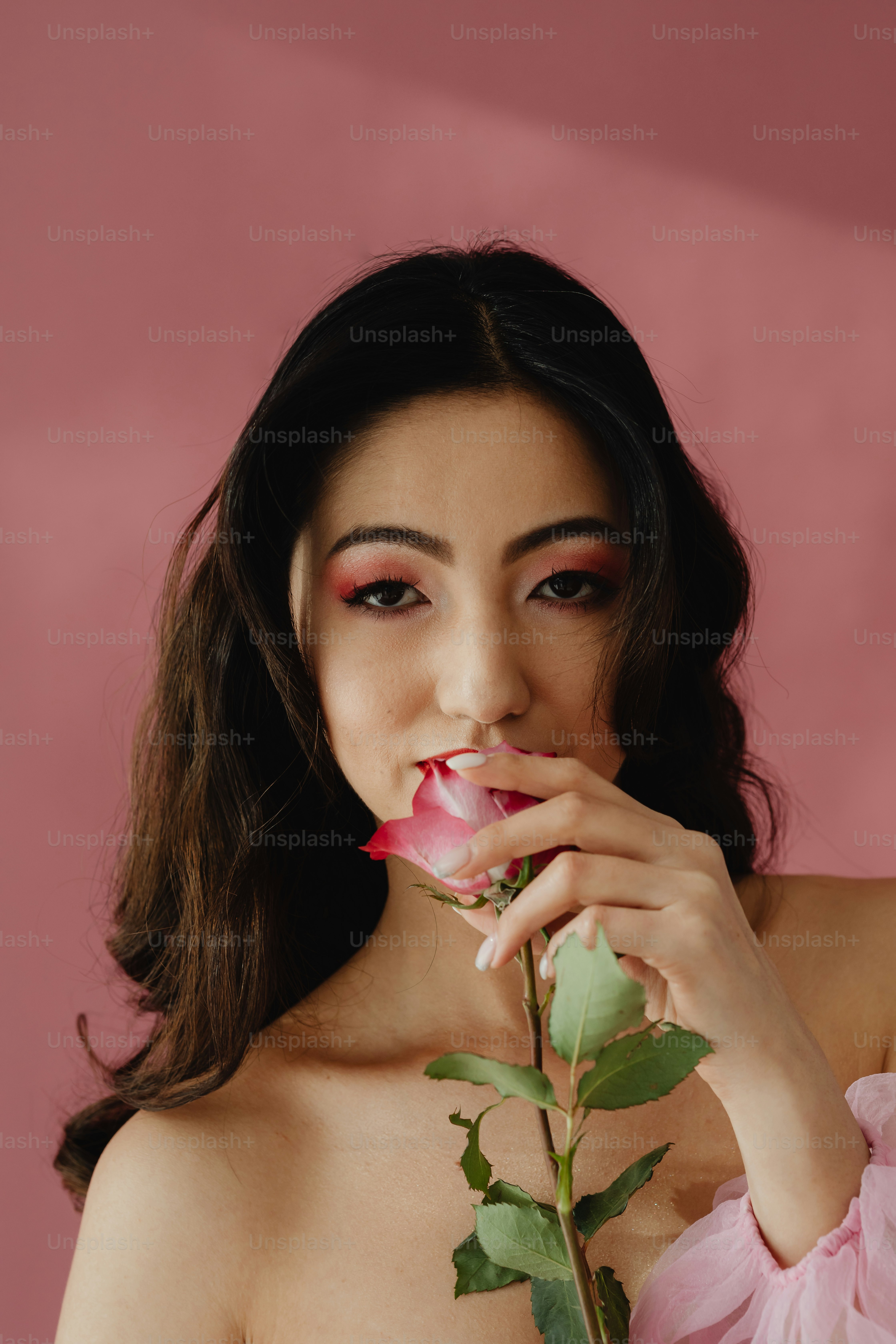 Una mujer con un vestido rosa sosteniendo una rosa