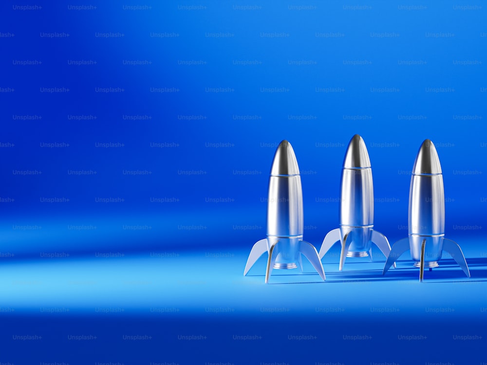 three silver bullet shaped objects on a blue background