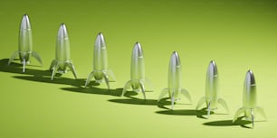Una fila de cohetes de metal sentados encima de una superficie verde