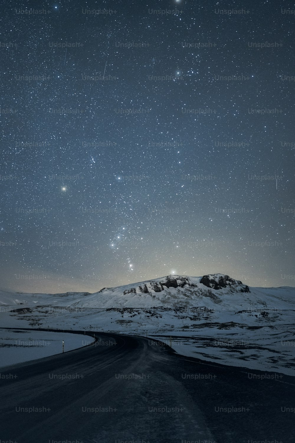 the night sky with stars above a snowy mountain