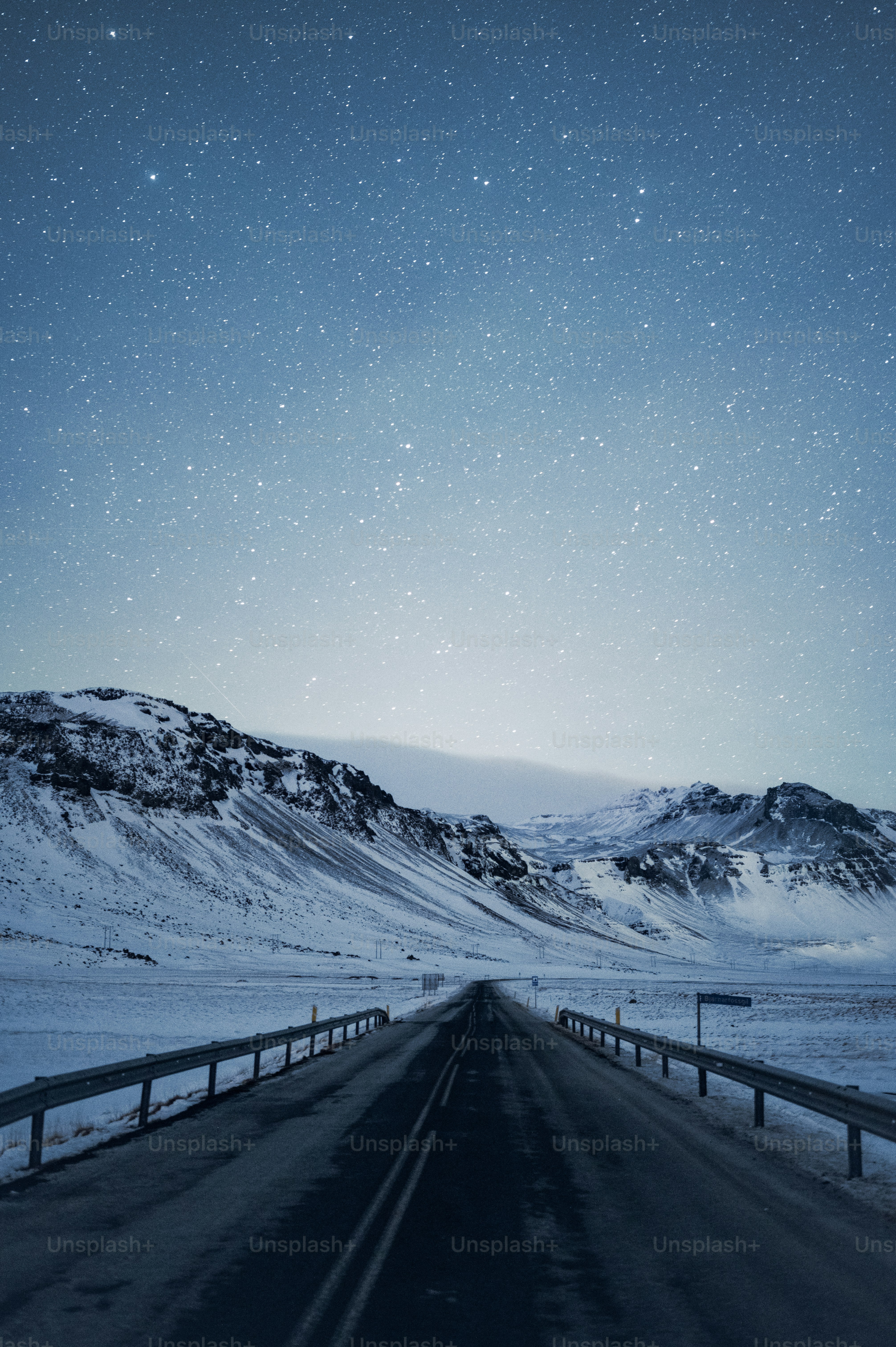 uma estrada com neve no chão e montanhas ao fundo