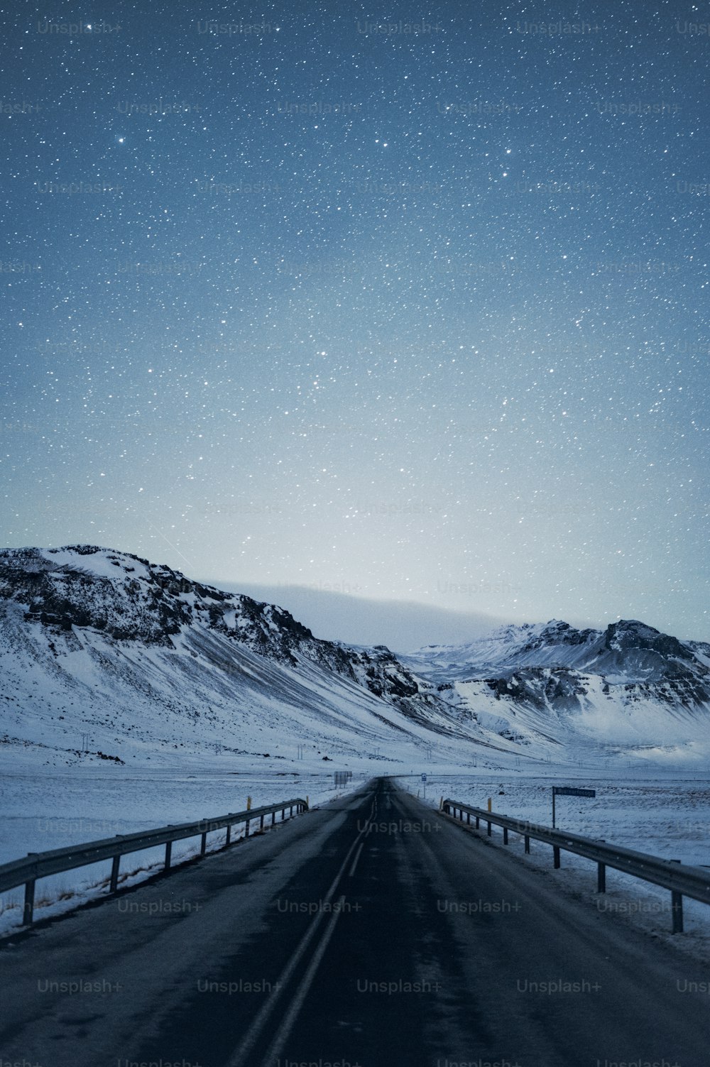 Eine Straße mit Schnee auf dem Boden und Bergen im Hintergrund