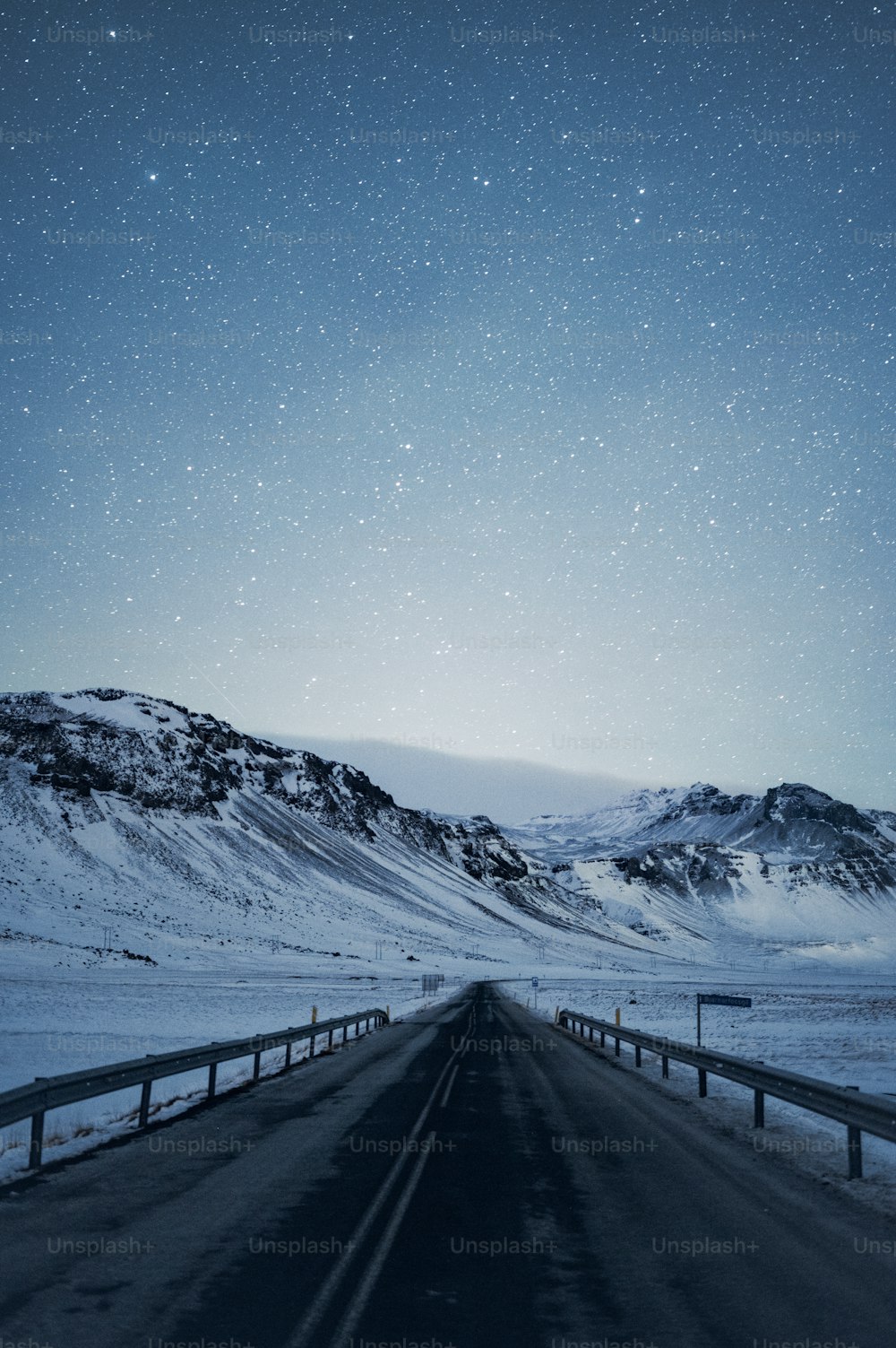 a road with snow on the ground and mountains in the background