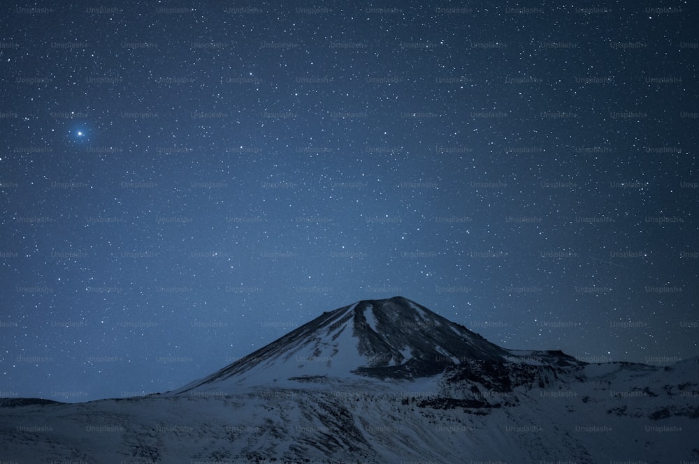 a snow covered mountain under a star filled sky