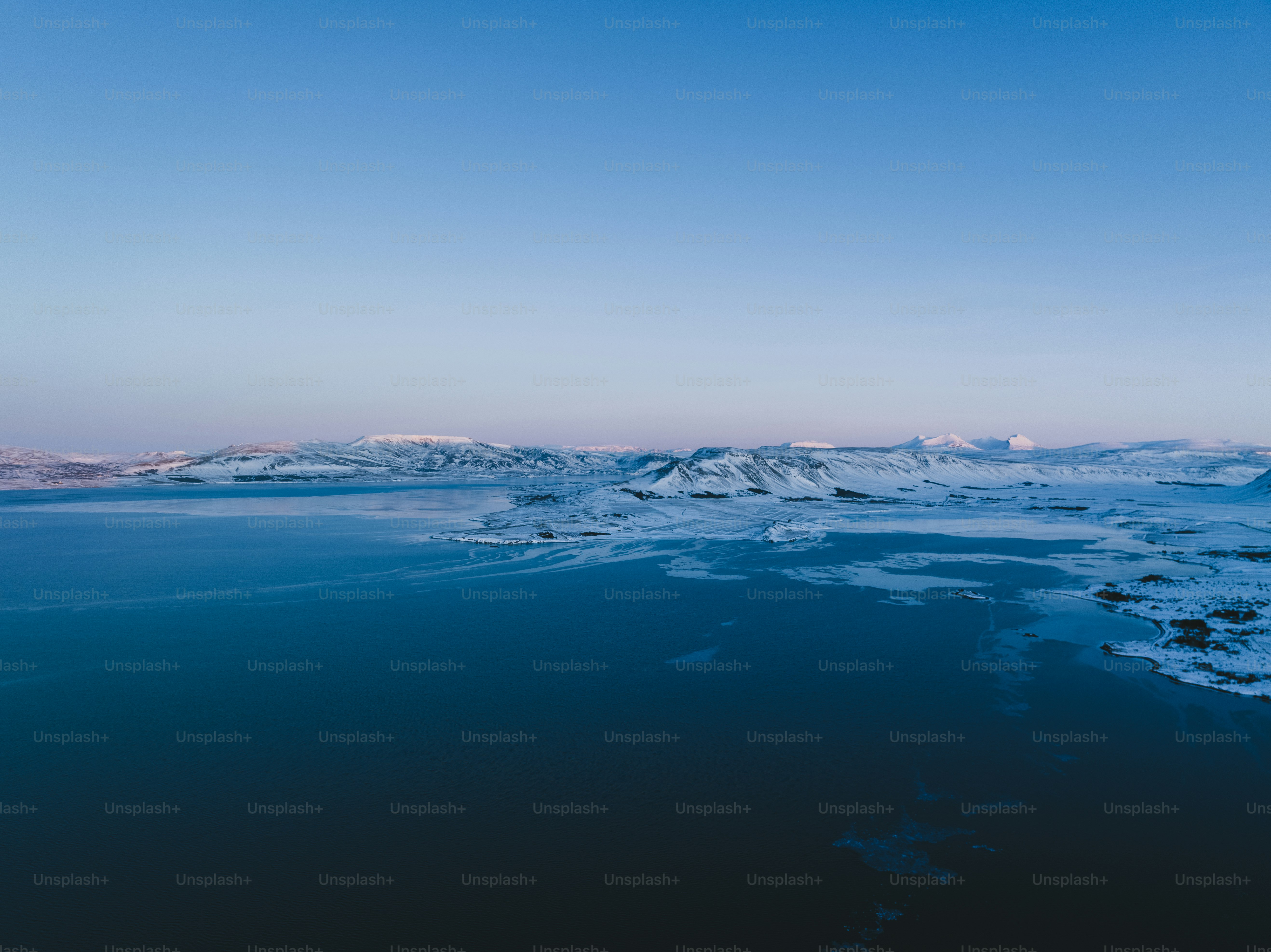 a large body of water surrounded by snow covered mountains