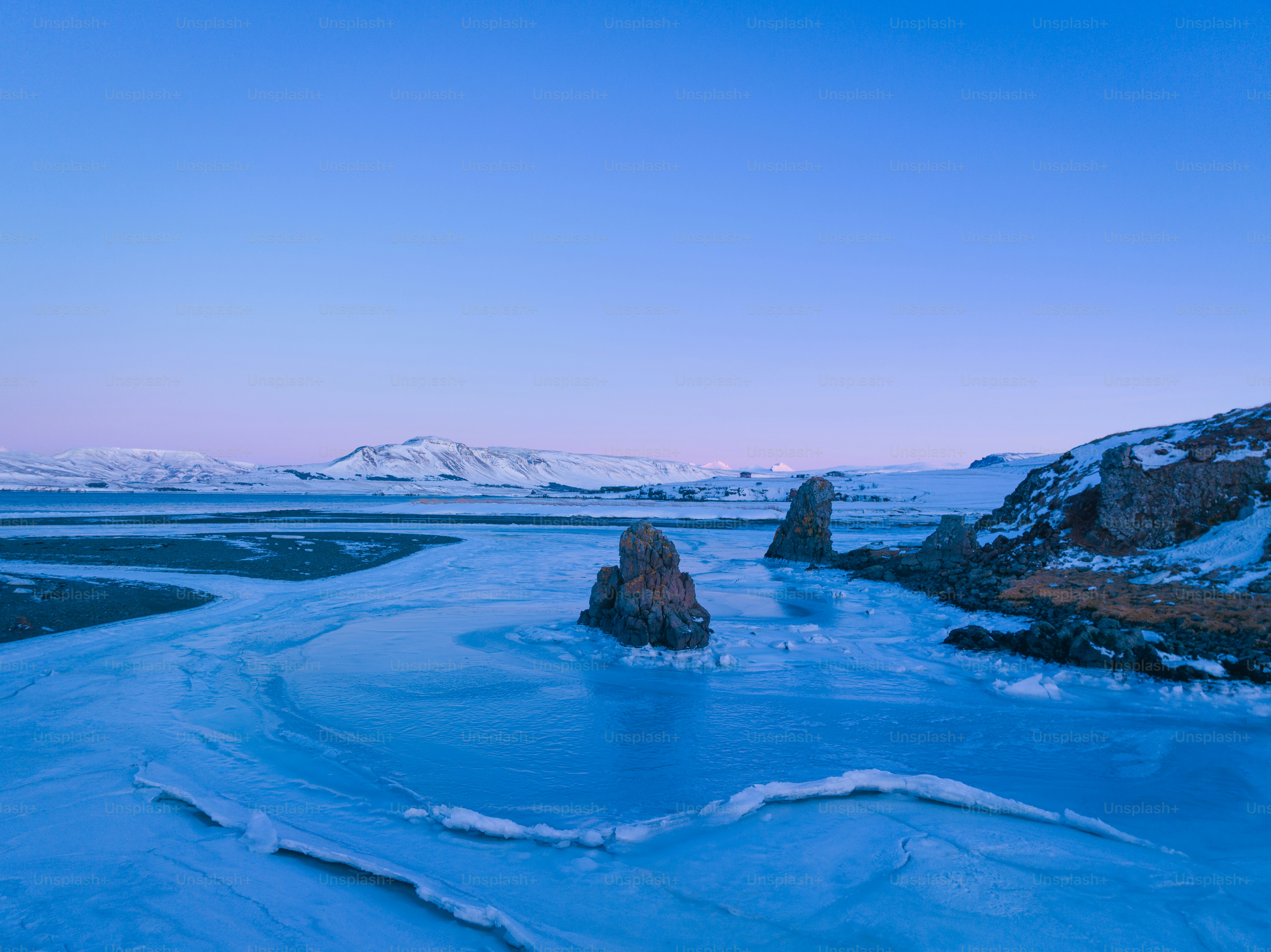 a body of water surrounded by snow covered mountains