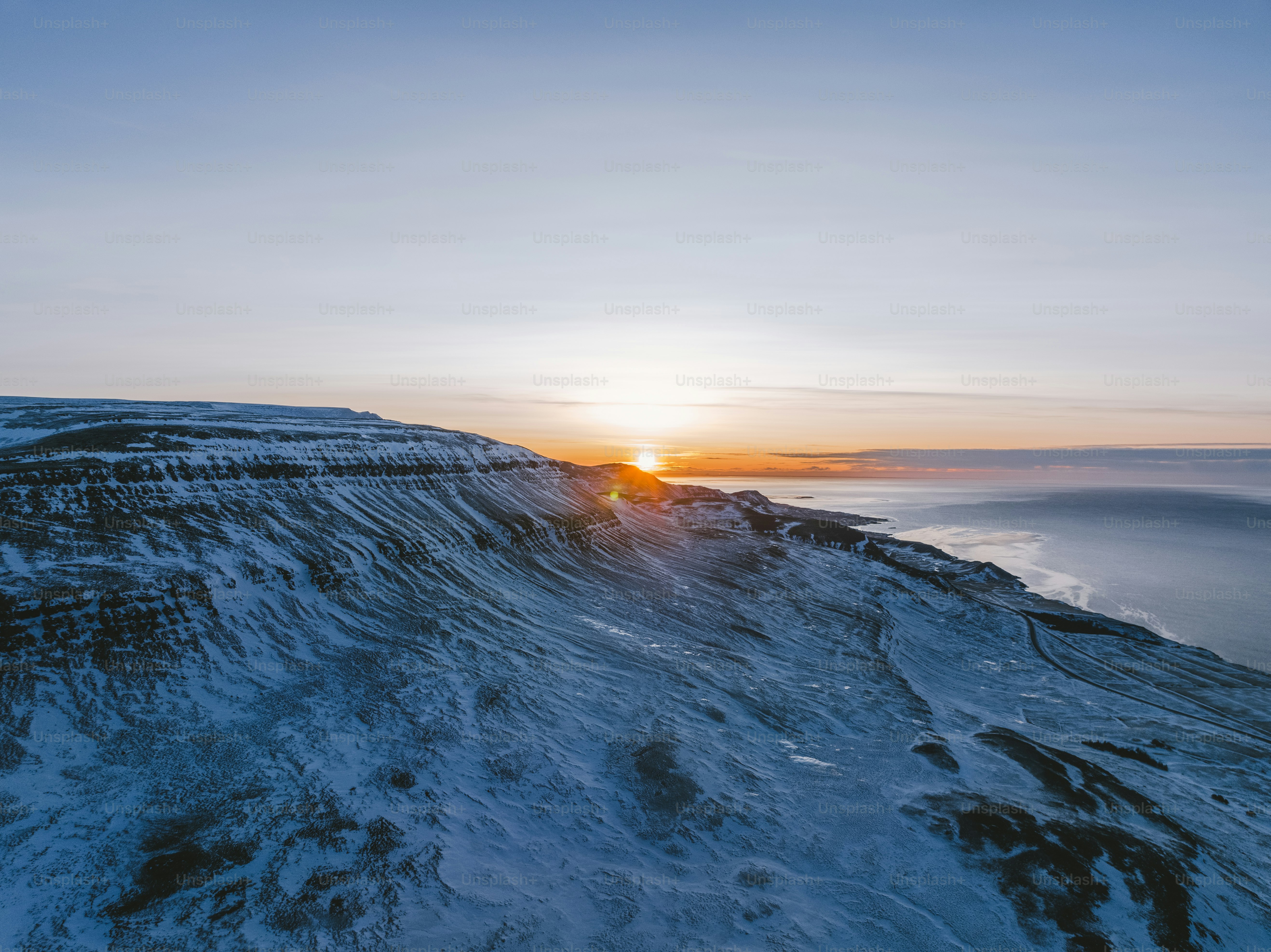The sun is setting over a snowy mountain photo – Rising sun Image on ...
