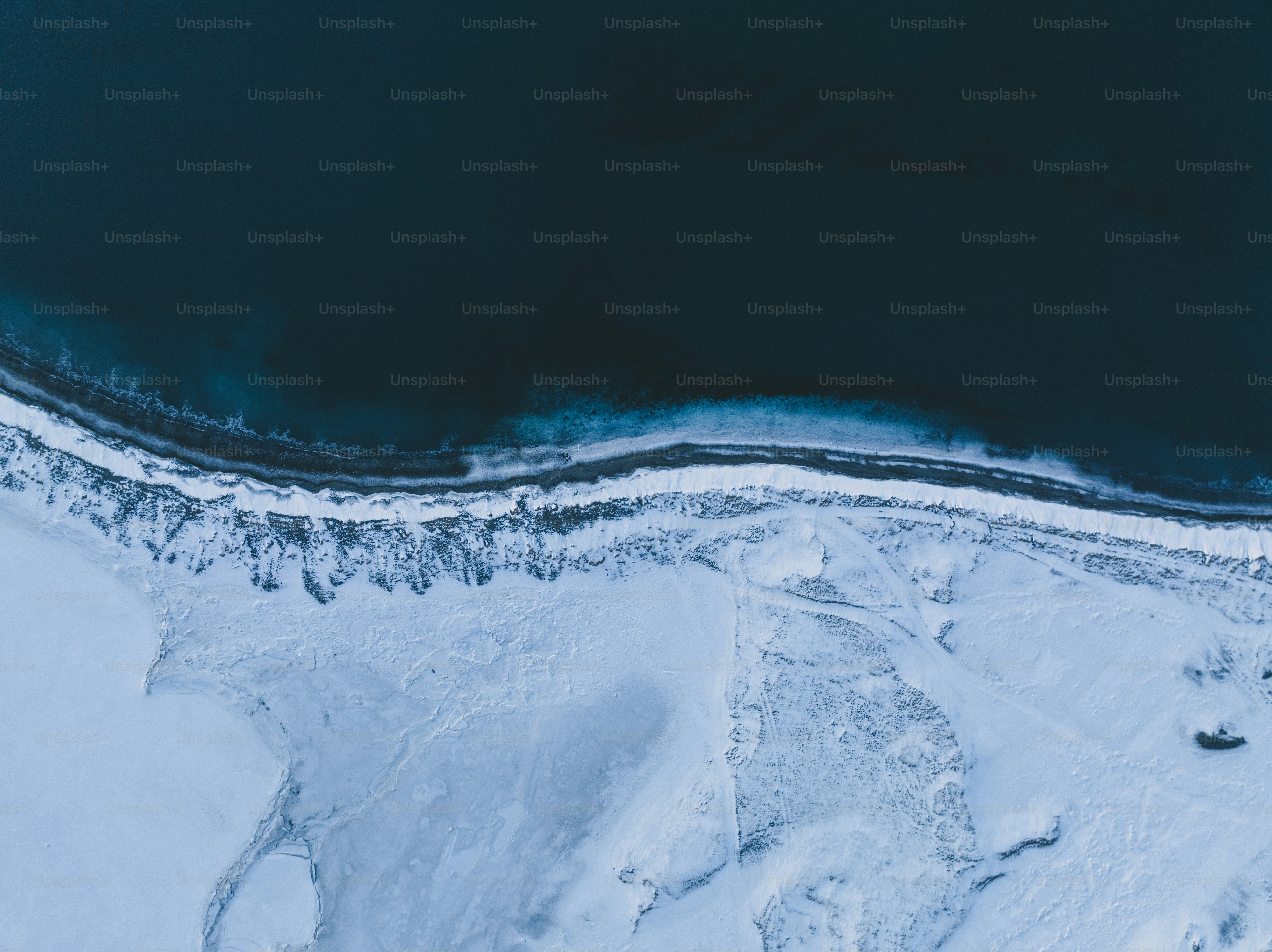 an aerial view of snow covered ground and water