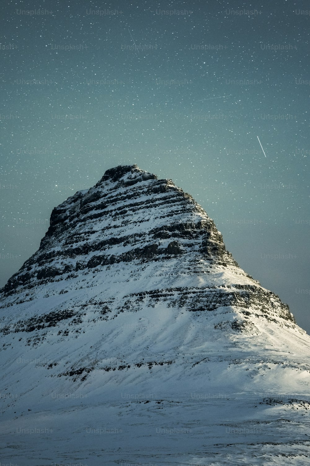 Una montagna coperta di neve sotto un cielo pieno di stelle