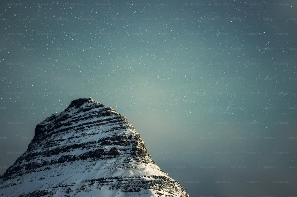 una montaña cubierta de nieve bajo un cielo lleno de estrellas