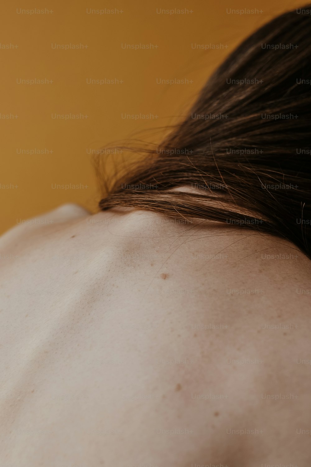 un gros plan du dos d’une personne avec un fond jaune