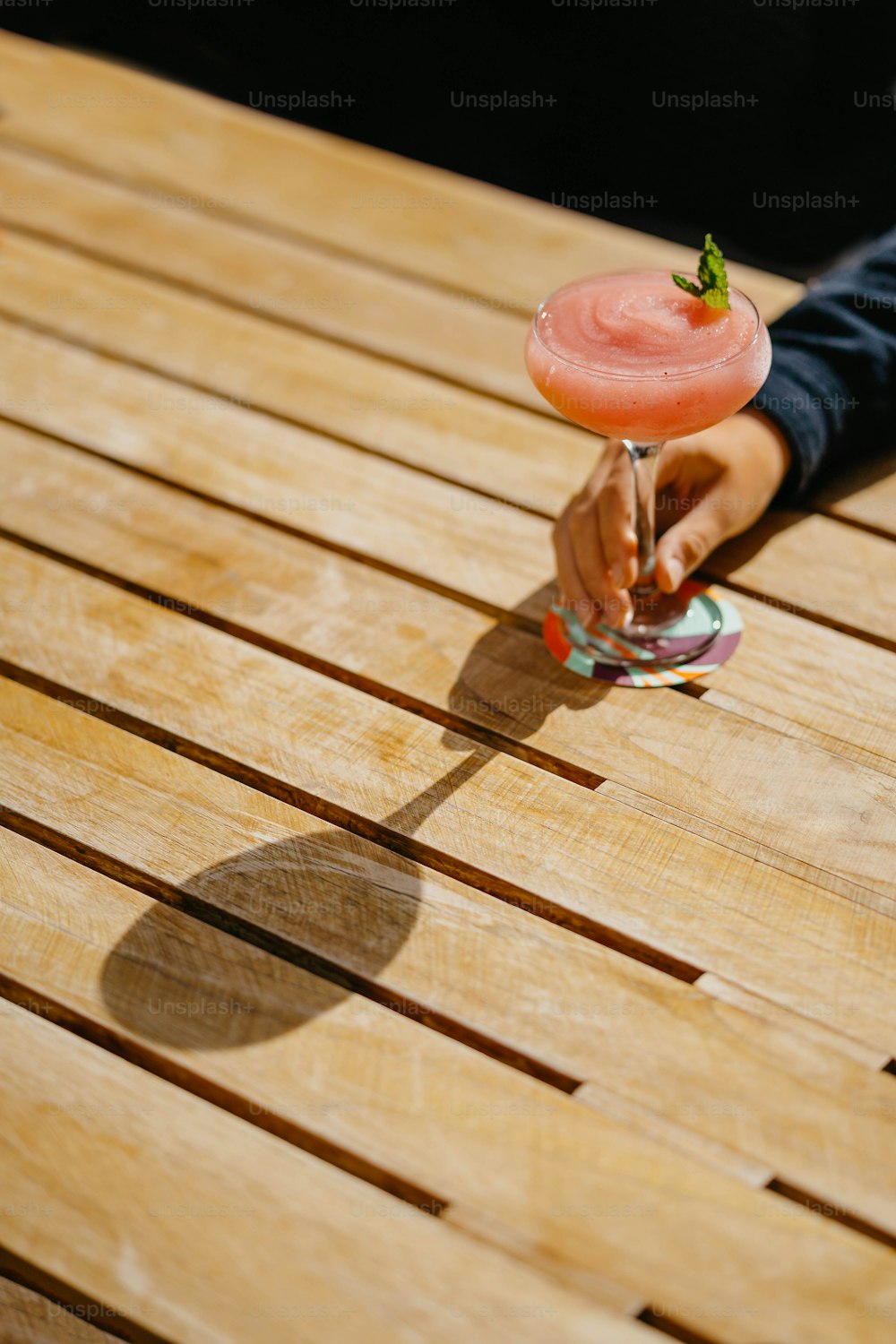 una persona sosteniendo una bebida encima de una mesa de madera