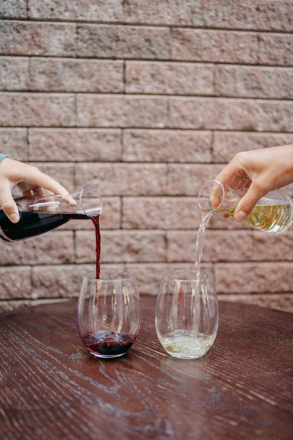 テーブルの上のワイングラスにワインを�注ぐ人