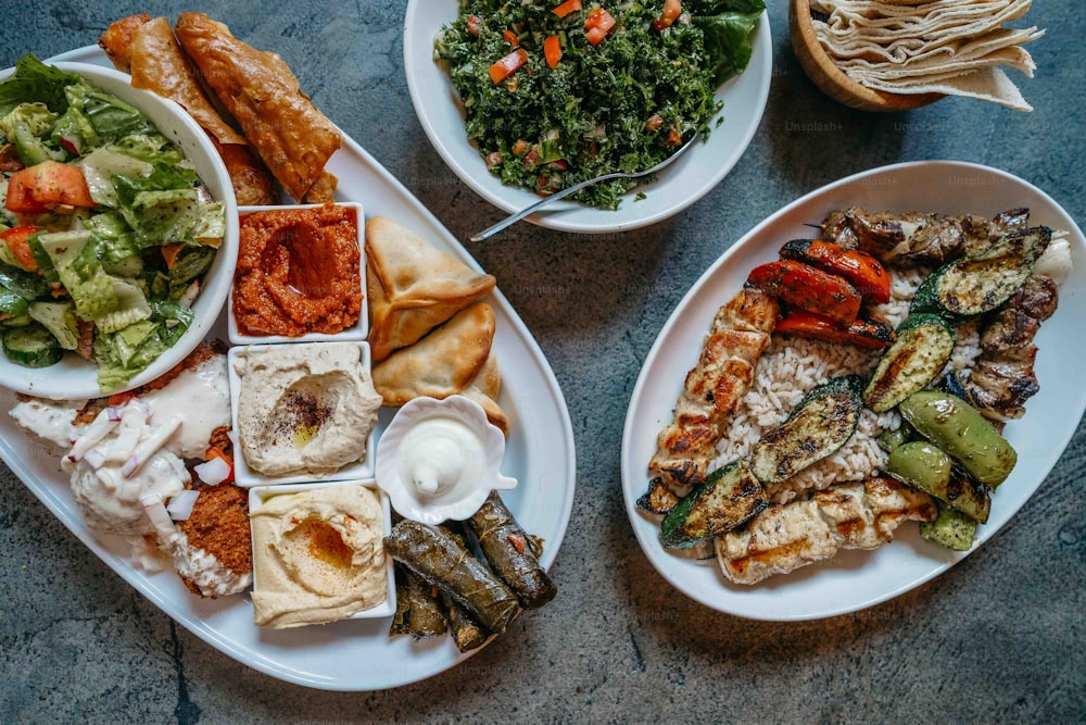 una mesa cubierta con platos de comida junto a un tazón de ensalada