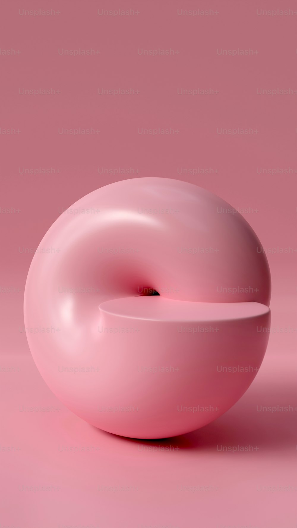 a pink donut sitting on top of a pink surface