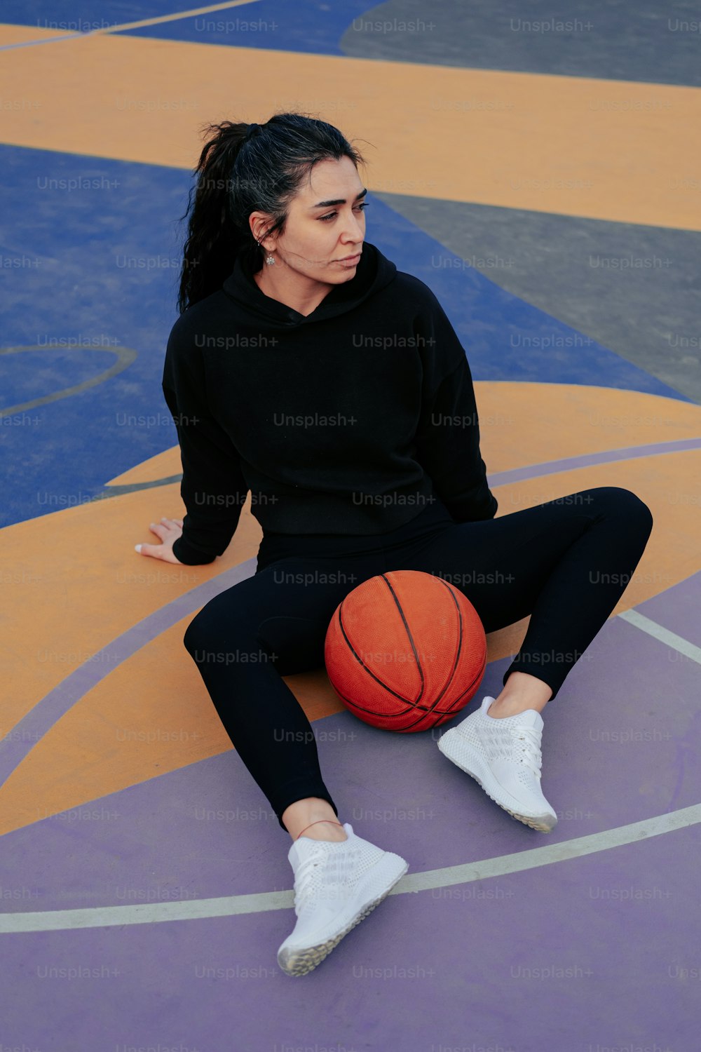 a woman sitting on a basketball court holding a basketball