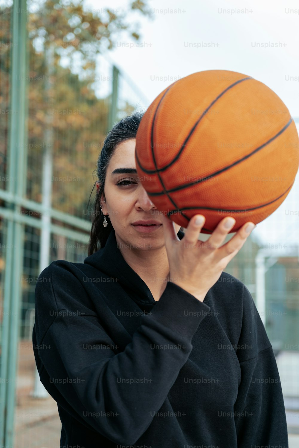uma mulher segurando uma bola de basquete até o rosto