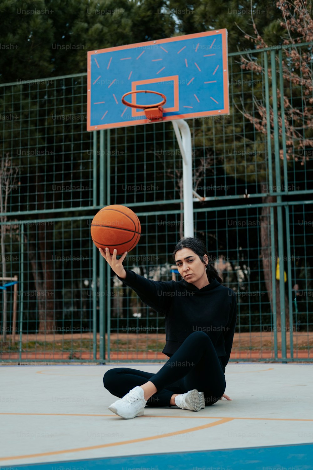 그녀의 손에 농구공을 들고 땅에 앉아 있는 여자