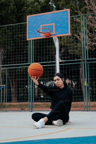 a woman sitting on the ground with a basketball in her hand