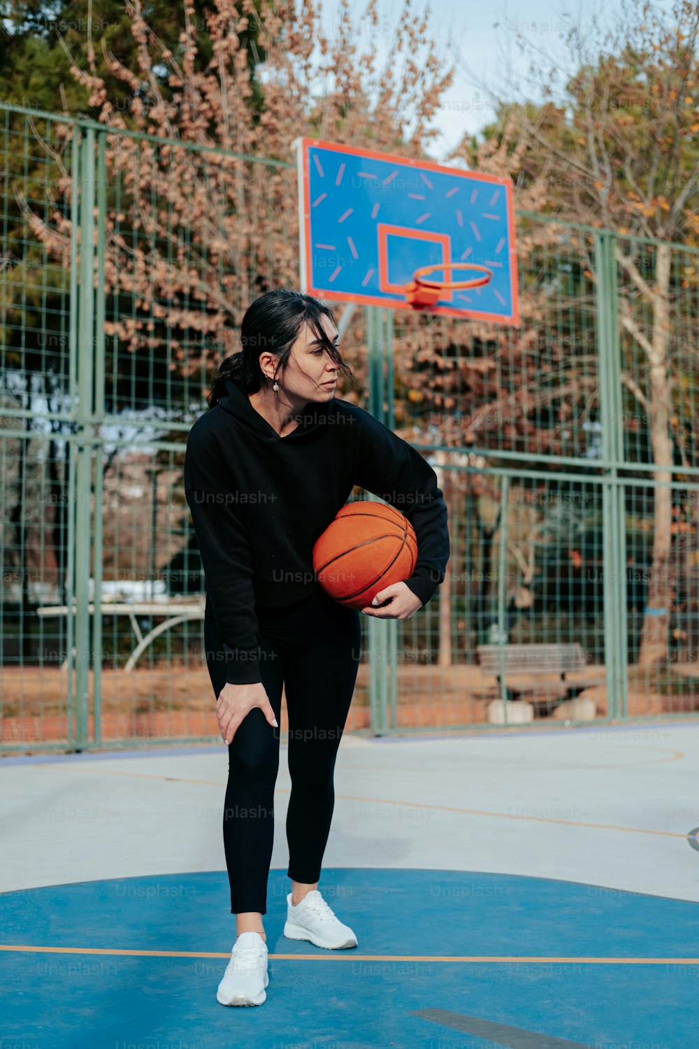 a woman holding a basketball while standing on a basketball court
