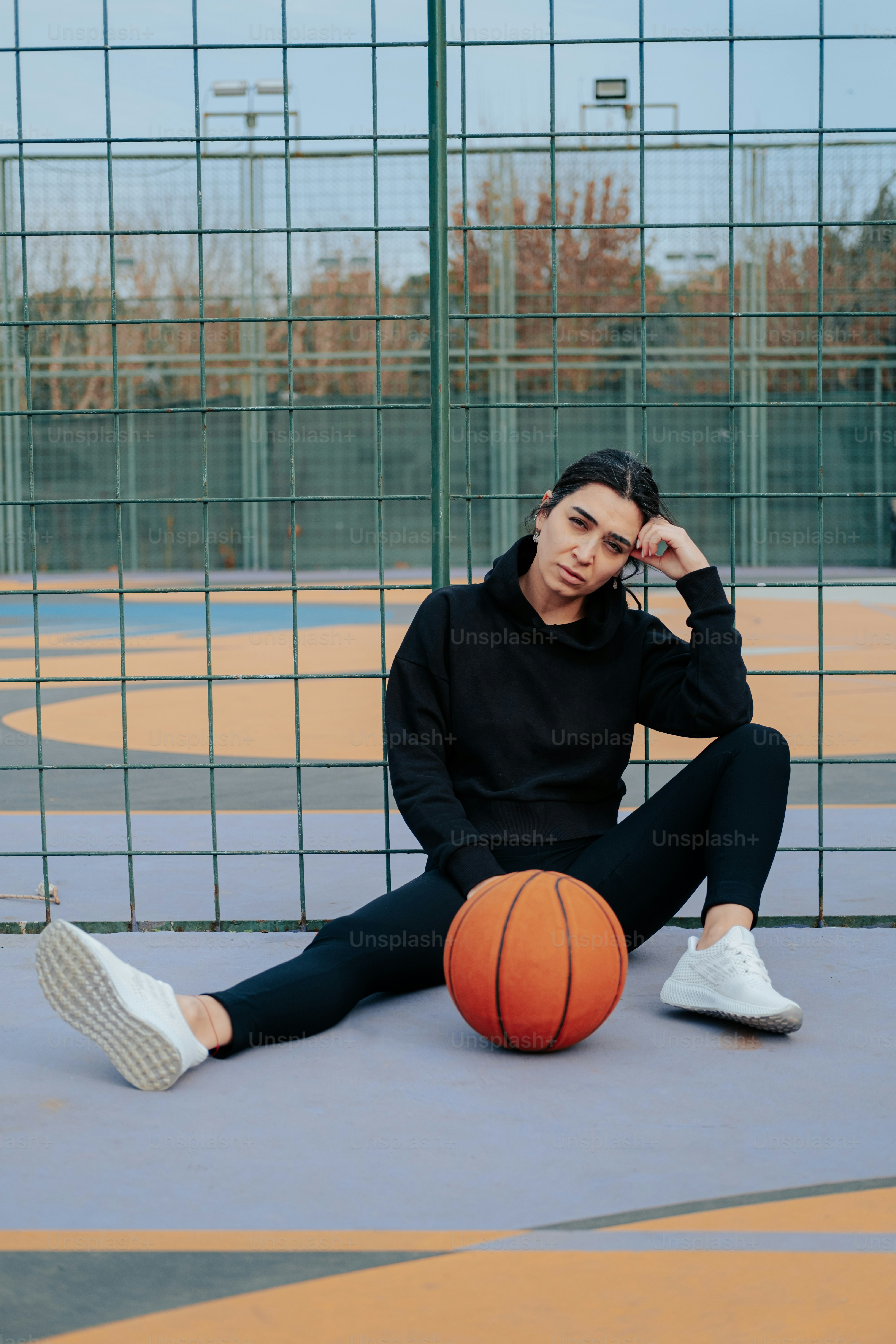 a woman sitting on the ground with a basketball