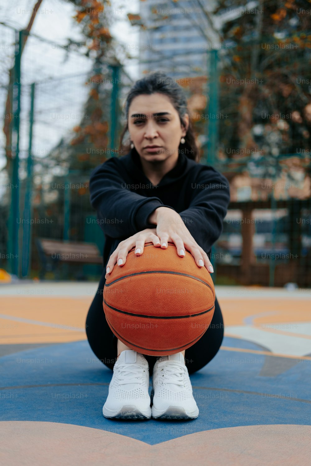 Una mujer sentada en el suelo sosteniendo una pelota de baloncesto