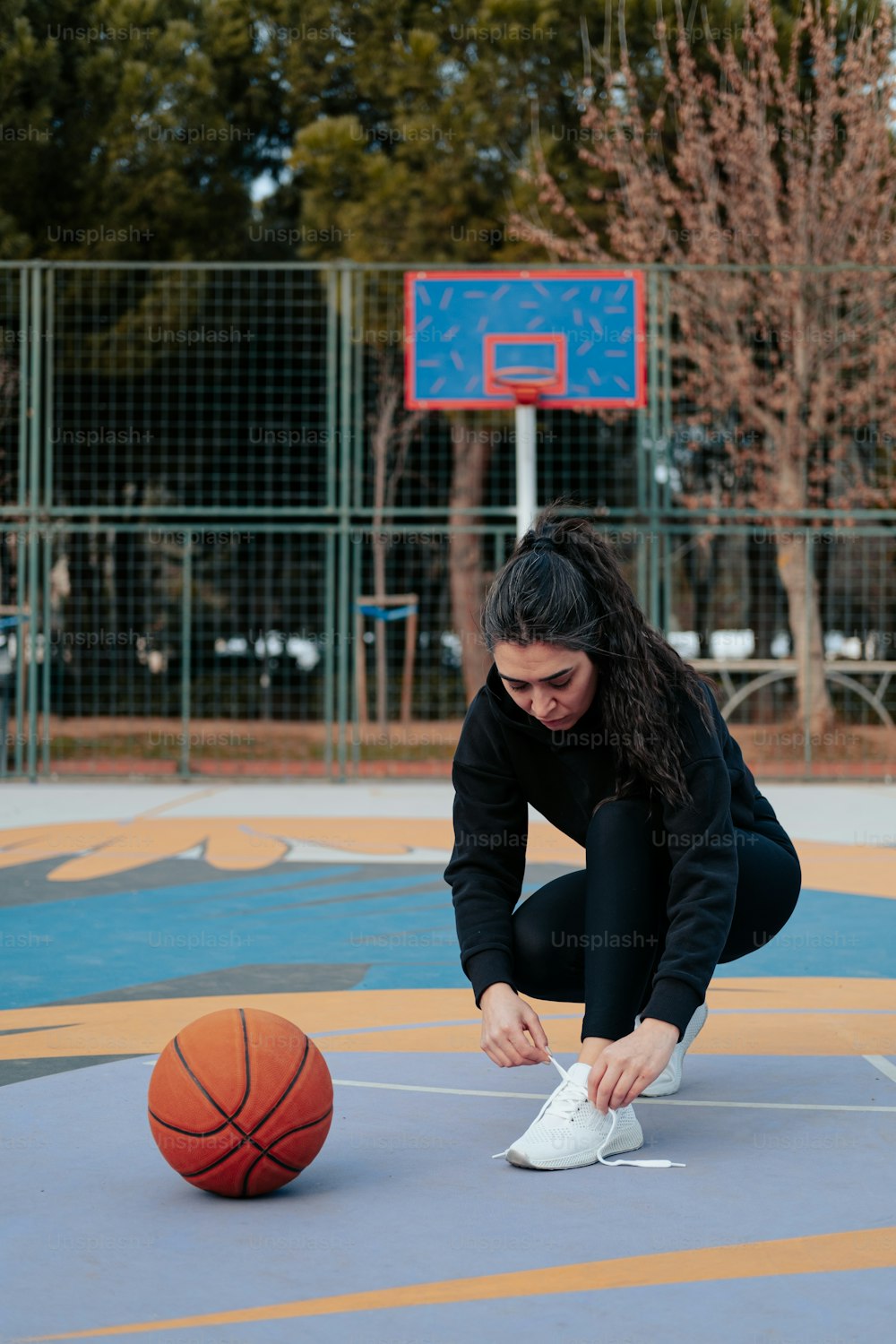 a woman is tying her shoes on a basketball court