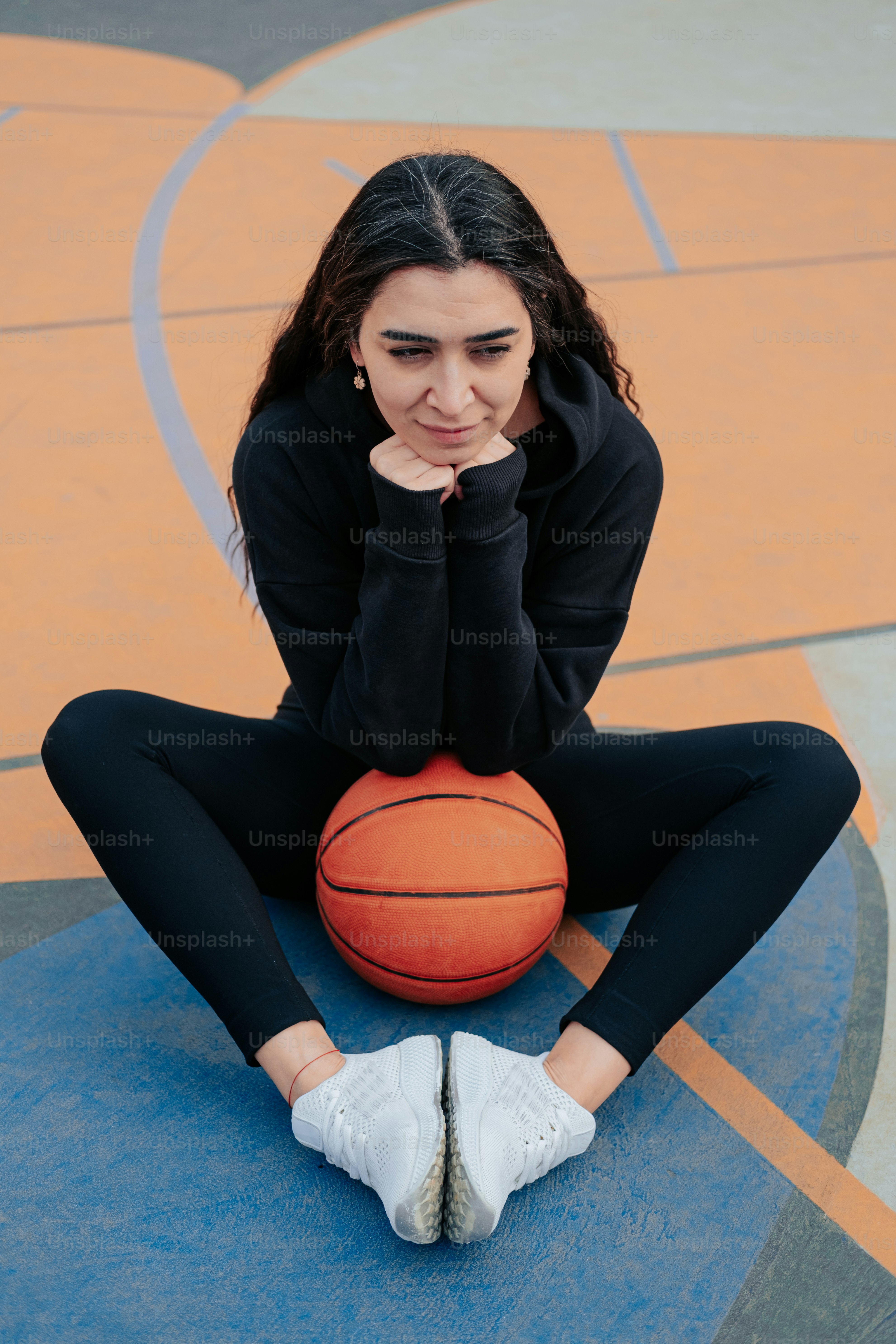 a woman sitting on a basketball court holding a basketball