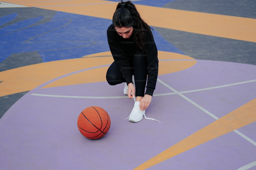 バスケットボールコートの上に靴を結ぶ女性