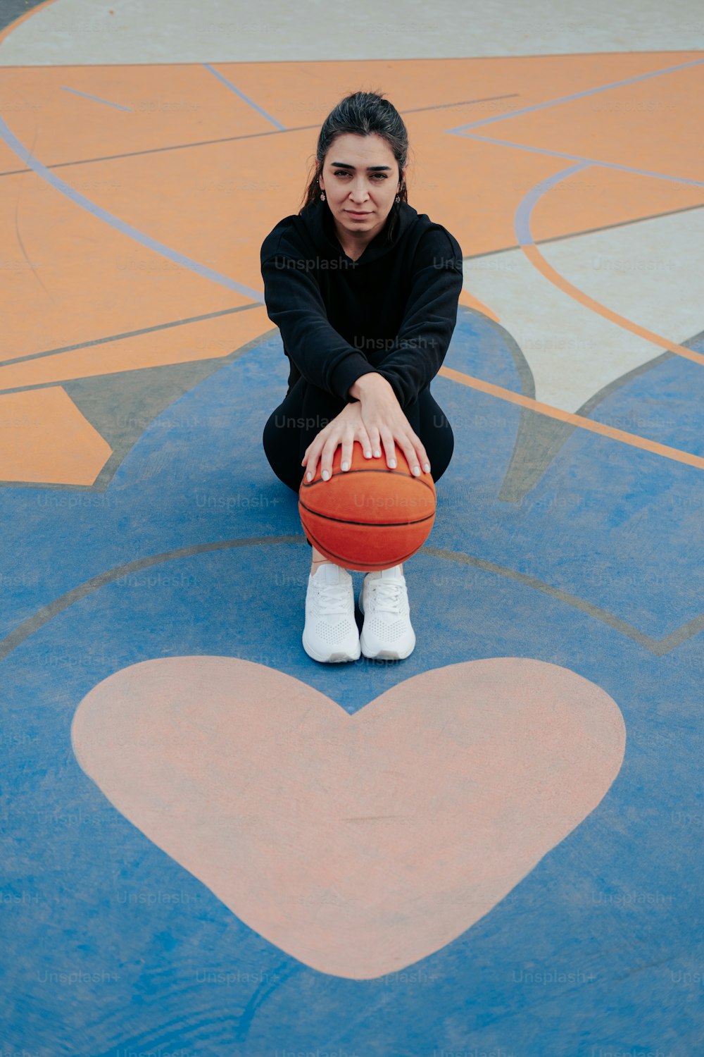 Una mujer sentada en el suelo sosteniendo una pelota de baloncesto