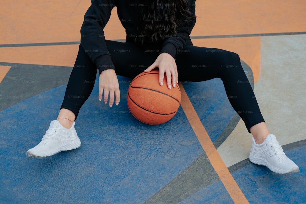 a woman sitting on a basketball court holding a basketball