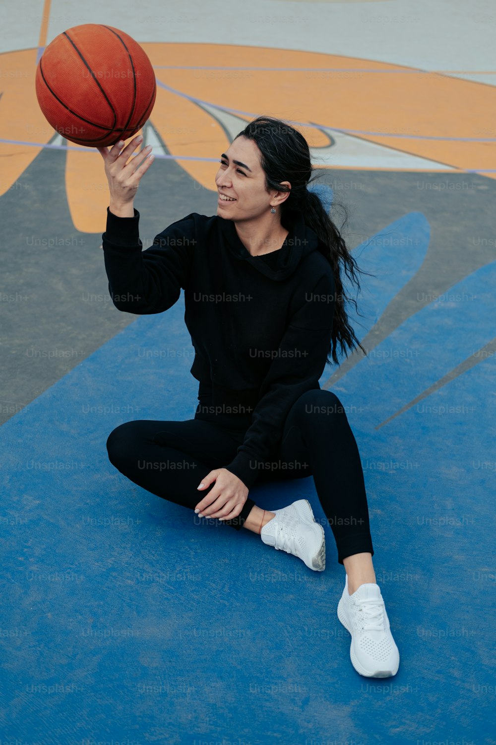 une femme assise par terre tenant un ballon de basket