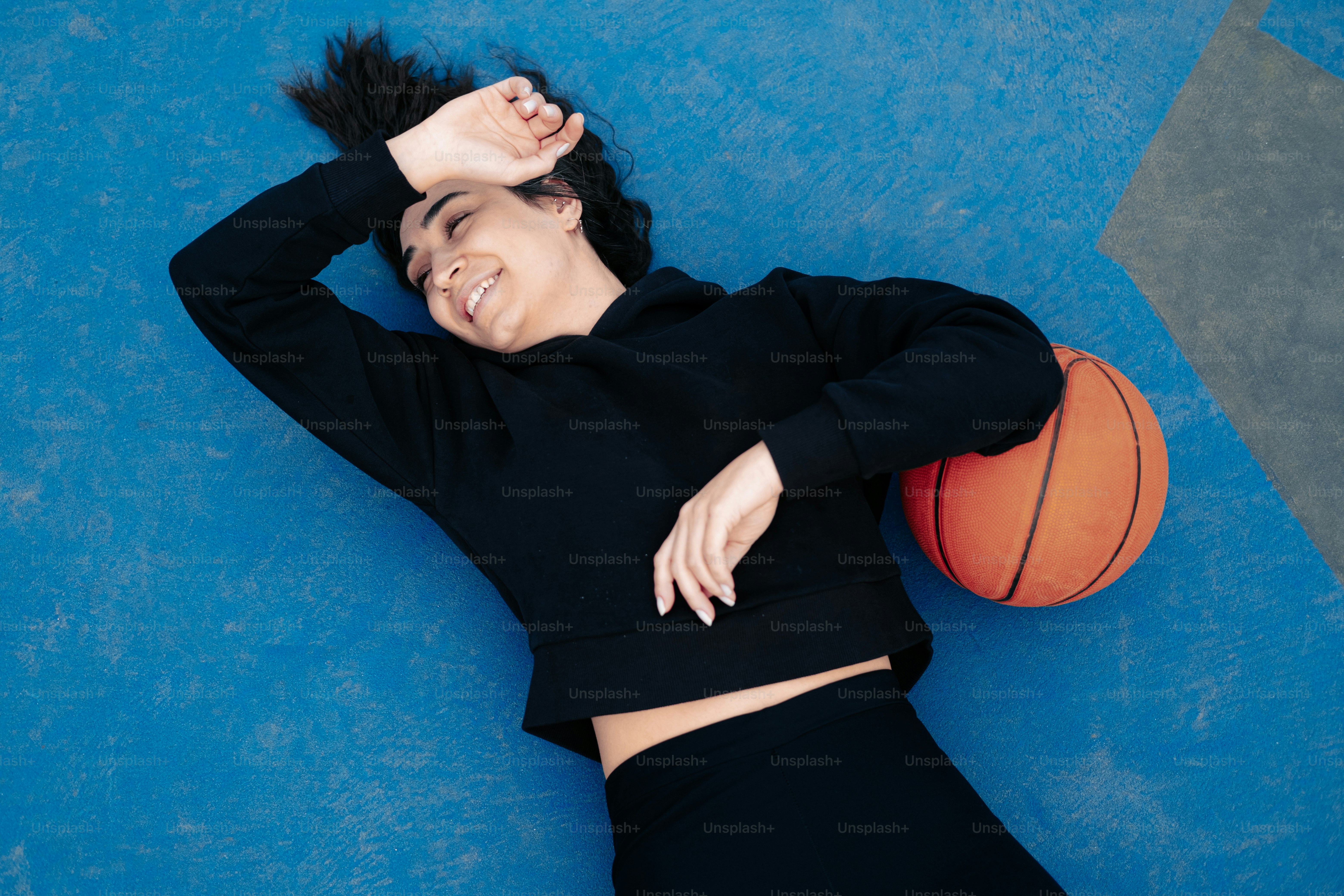 a woman laying on the ground with a basketball