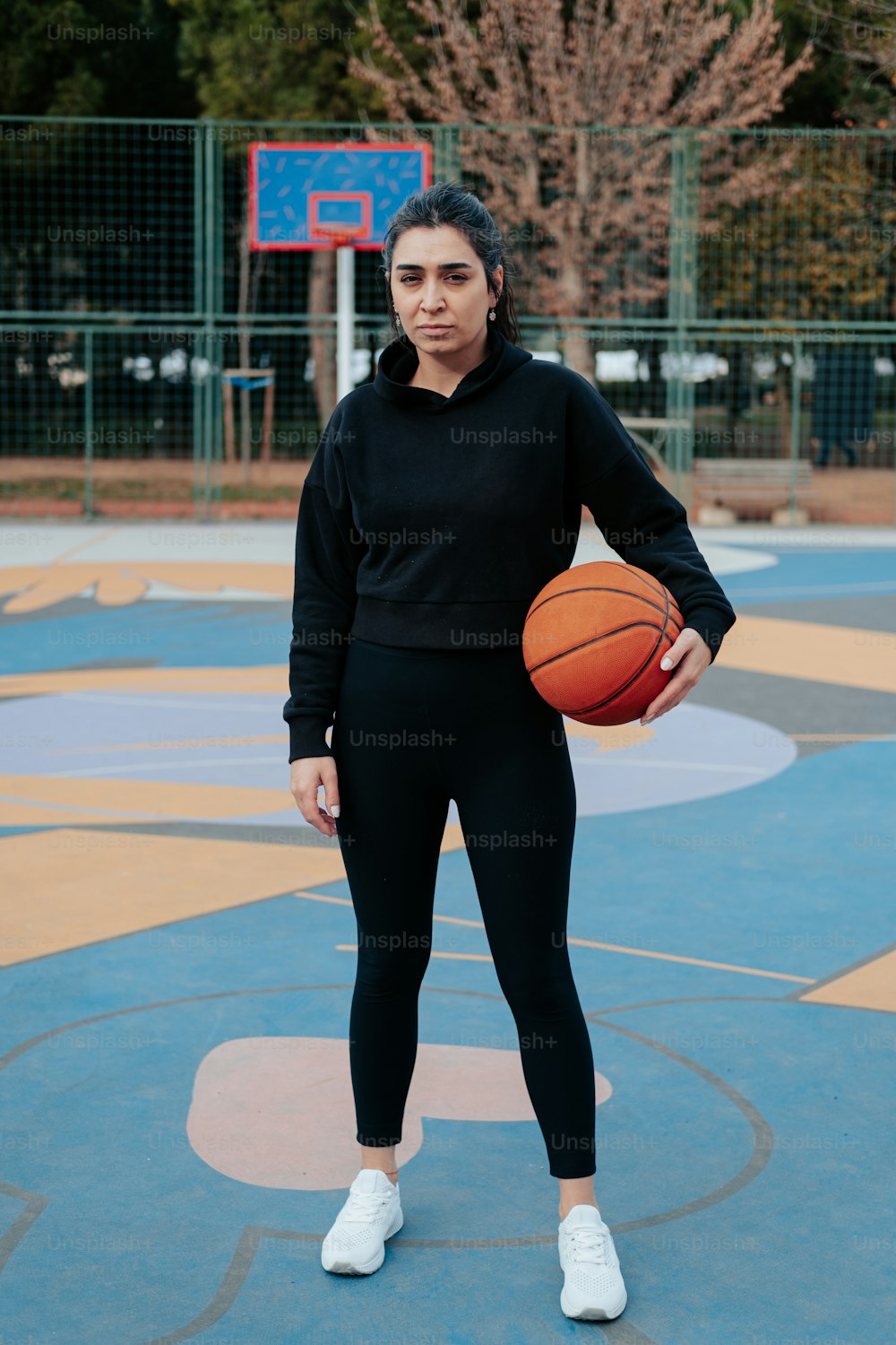 Una mujer sosteniendo una pelota de baloncesto en una cancha de baloncesto