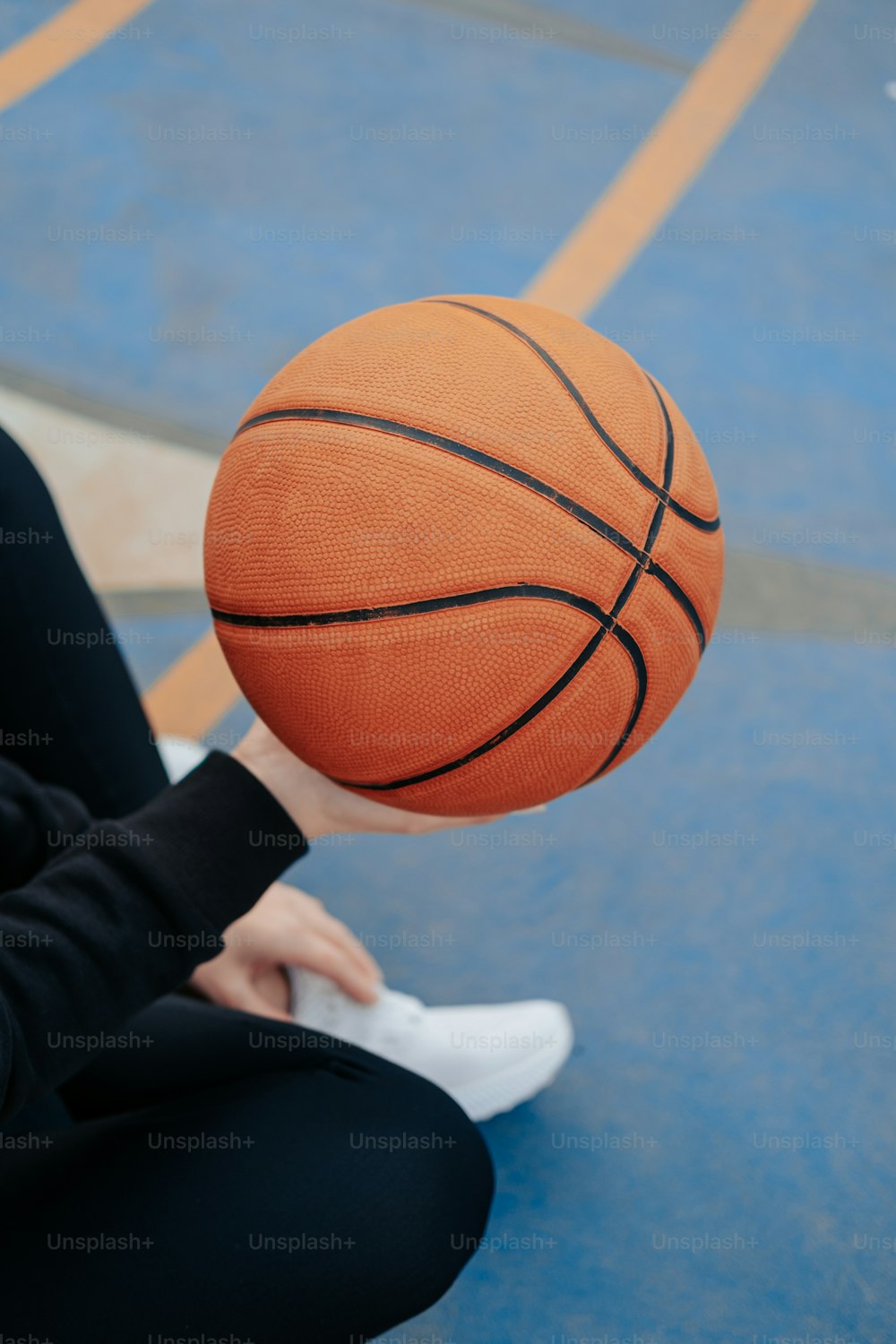 eine Person, die mit einem Basketball in der Hand auf dem Boden sitzt