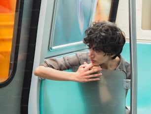 a young man leaning against a bus door